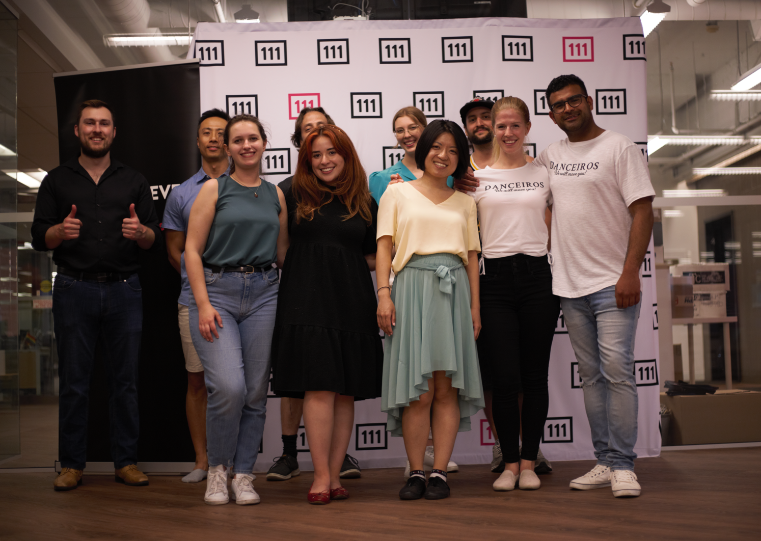 Group of dance students with their salsa instructors in front of a corporate logo banner. The corporate event took place at the office after work.